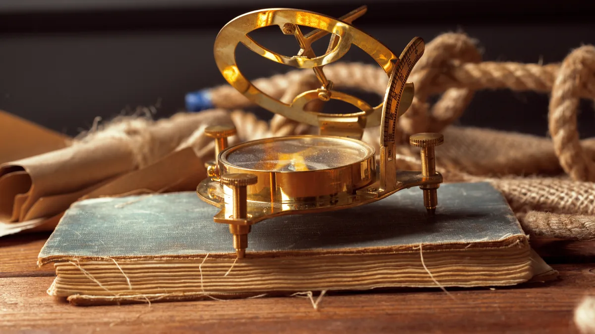 Instrumento de medición antiguo de latón sobre un libro envejecido, evocando la historia de las matemáticas.