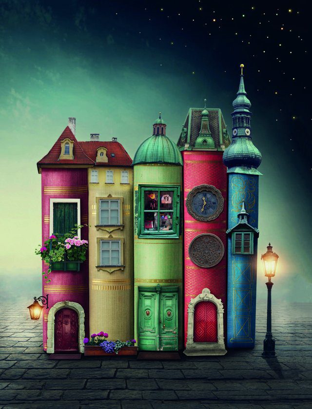 Imagen de portada del Texto del Estudiante de Lenguaje 2° Básico: casas de colores con forma de libros sobre un adoquinado, de noche y con un farol encendido
