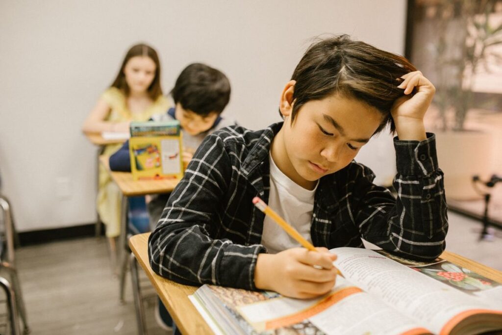 Alumno escribiendo en su cuaderno durante una actividad en clase.
